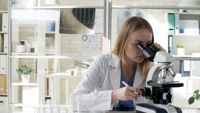 Mujer-en-bata-de-laboratorio-con-microscopio