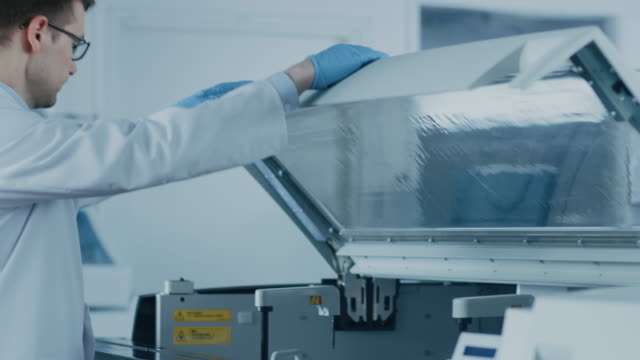 Wissenschaftlicher-Mitarbeiter-setzt-Reagenzgläser-mit-Blutproben-in-die-Maschine-zu-analysieren.-Innovativen-pharmazeutischen-Labor-mit-modernen-medizinischen-Geräten-Genetik-forschen.