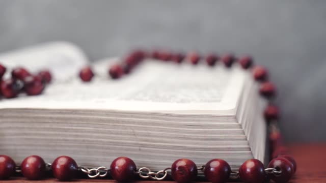Bible-and-the-crucifix-beads-on-a-red-wooden-table.-Beautiful-background.-Religion-concept-close-up