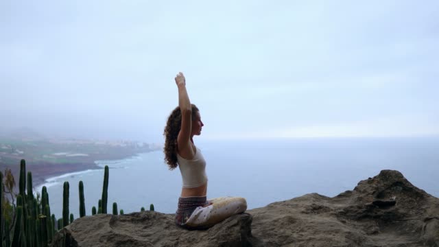Frau-bei-Sonnenaufgang-auf-einem-Felsen-in-den-Bergen-meditieren.-Üben-Sie-Yoga-auf-outdoor.