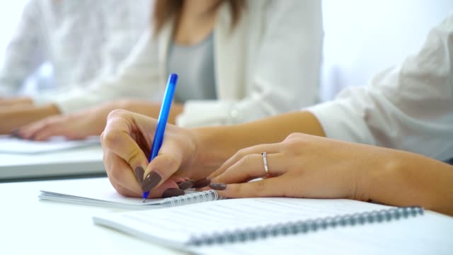 Closeup-jungen-männlichen-und-weiblichen-Studenten-Hände-schreiben-mit-Stiften-in-Notebook-im-Klassenzimmer