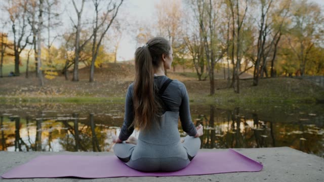 Young-woman-practicing-yoga-outdoors.-Female-meditate-outdoor-infront-of-beautiful-autumn-nature