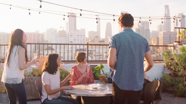 Freunde-versammelt-auf-Dachterrasse-für-Party-mit-Skyline-der-Stadt-im-Hintergrund