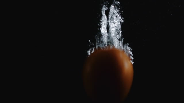 Naranja-caída-a-través-del-agua-sobre-fondo-negro
