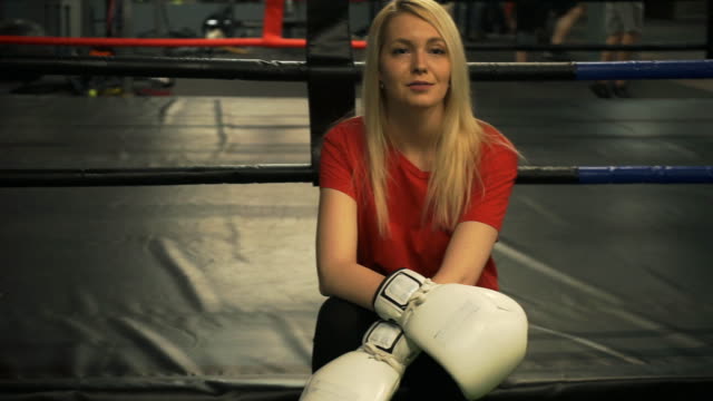 The-girl-the-boxer-sits-on-a-ring-looks-in-the-camera-and-is-surprised