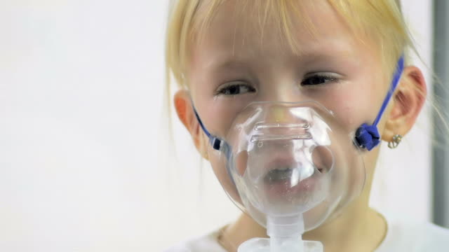 Primer-plano-de-una-niña-de-cuatro-años-en-una-máscara-de-gas-de-respiración-a-través-de-un-inhalador-en-el-hospital-en-cámara-lenta.