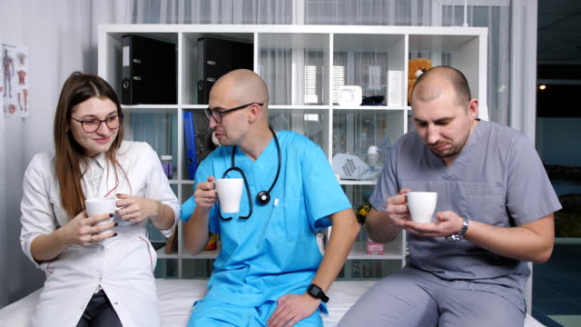 Three-doctors-in-the-staffroom-talk-and-drink-coffee-at-the-break.