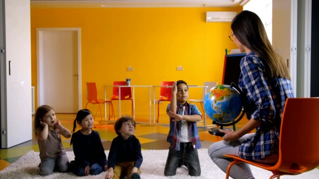Kinder-im-Vorschulalter-lernen-Globus-zusammen-mit-Lehrer