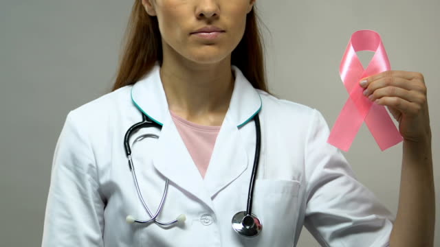 Médico-sosteniendo-la-cinta-rosa,-el-concepto-de-conciencia-de-cáncer-de-mama,-chequeo-preventivo