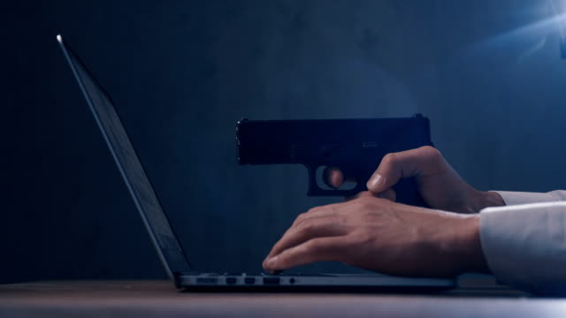 Arm-with-gun-aims-at-a-screen-of-laptop.-Cyber-robbery.