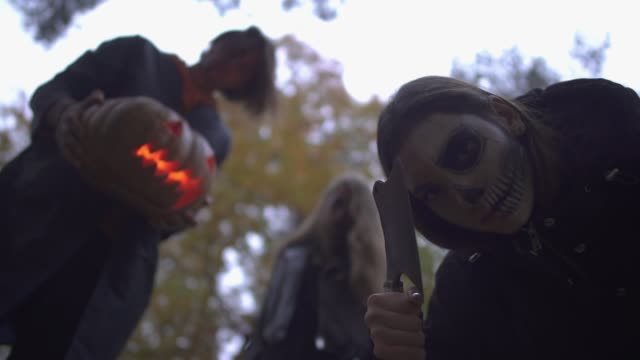 Mann-und-zwei-Frauen-in-Halloween-Kostümen-schauen-auf-das-Opfer-mit-ernsten-beängstigend-Gesichter-im-Herbst-Park.