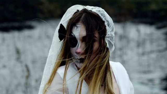 A-woman-with-spooky-make-up-for-Halloween-in-a-white-bride-dress.-Slow-motion.-HD