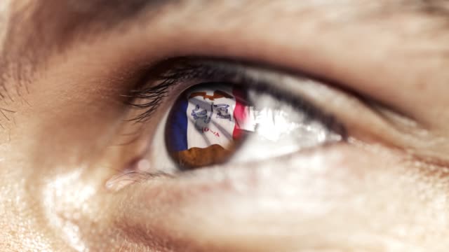Man-with-brown-eye-in-close-up,-the-flag-of-Iowa-state-in-iris,-united-states-of-america-with-wind-motion.-video-concept