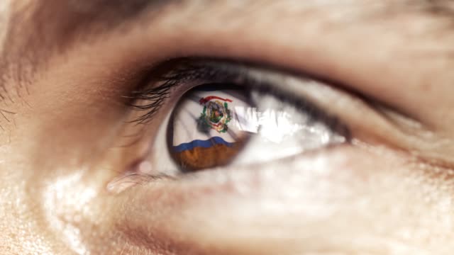 Man-with-brown-eye-in-close-up,-the-flag-of-West-Virginia-state-in-iris,-united-states-of-america-with-wind-motion.-video-concept