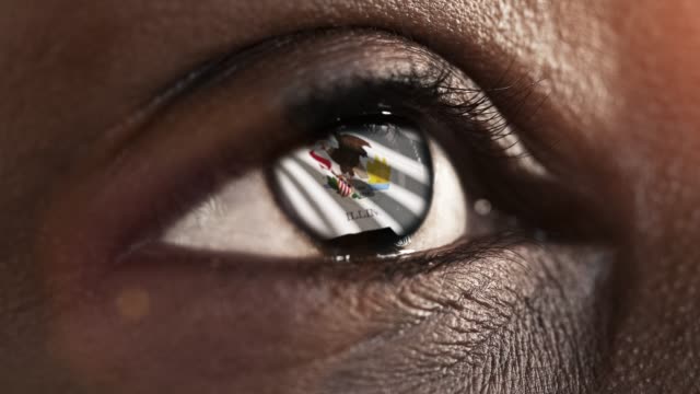 Woman-black-eye-in-close-up-with-the-flag-of-Illinois-state-in-iris,-united-states-of-america-with-wind-motion.-video-concept