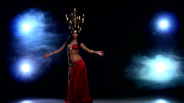 Attractive-belly-dancer-girl-starts-dancing-with-candles-on-her-head,-black,-smoke