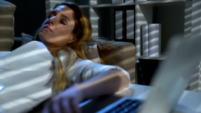 Tired-businesswoman-sleeping-on-the-couch-in-the-office-with-laptop-and-phone