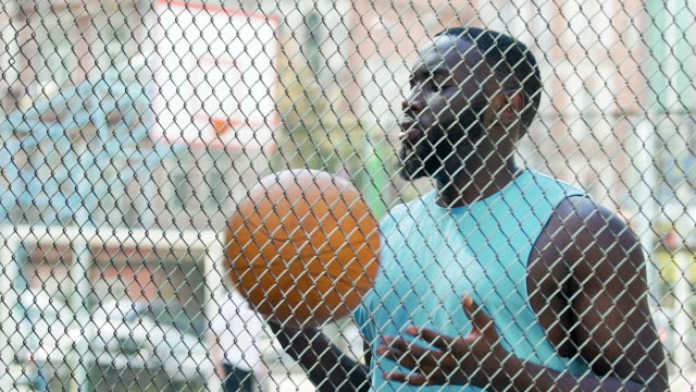 Hombre-negro-encarcelado-lanzar-bola-bajo-supervisión,-deportes-en-la-cárcel,-entrenamiento