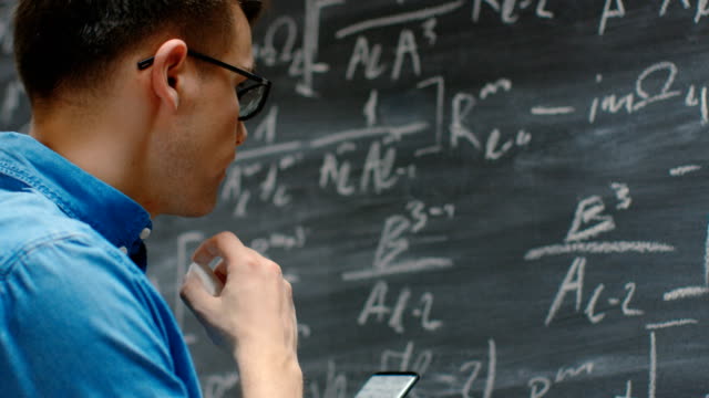 Brilliant-Young-Mathematician-Writes-Long-and-Complex-Math-Equation/-Formula-on-the-Blackboard.