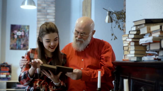 Ältere-Mann-liest-Buch-zusammen-mit-seiner-schönen-Enkelin