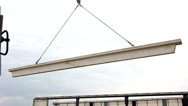 Worker-is-attaching-crane-hooks-to-concrete-joist-in-truck-trailer