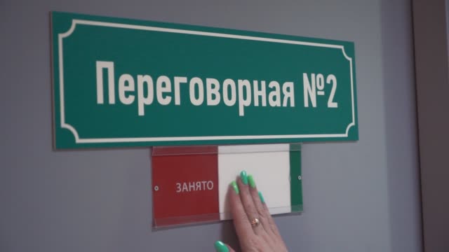 Female-hand-moves-paper-to-free-on-door-with-cyrillic-text-meeting-room