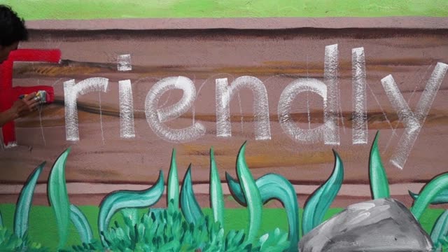 Mural-painter-draws-a-letter-F-on-school-wall.-time-lapse