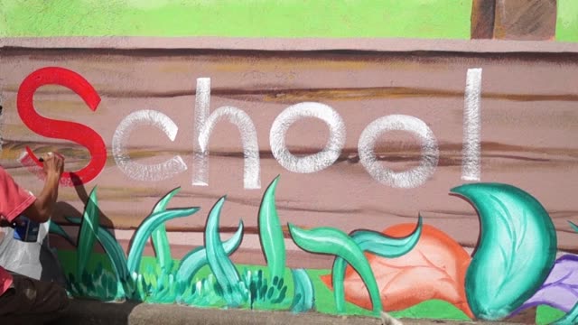 Mural-painter-draws-a-letter-S-on-school-wall.-time-lapse