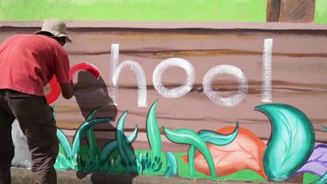 Mural-painter-draws-a-letter-c-on-school-wall.-time-lapse