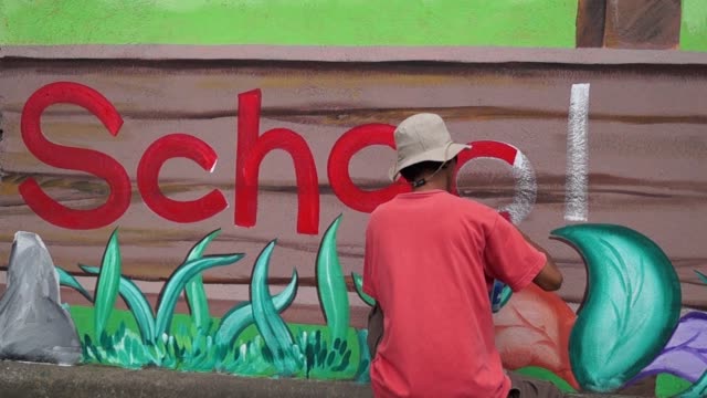 Mural-painter-draws-a-letter-o-on-school-wall.-time-lapse