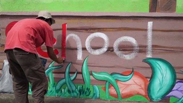 Mural-painter-draws-a-letter-h-on-school-wall.-time-lapse