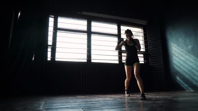 silhouette-beautiful-young-boxing-woman-training-punching-in-fitness-studio