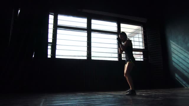 silhouette-beautiful-young-boxing-woman-training-punching-in-fitness-studio-slow-motion