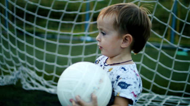 Kleiner-Junge-hält-den-Ball-in-seine-Hände-auf-dem-Fußballplatz
