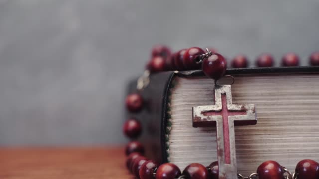 Bibel-und-Kreuz-Perlen-auf-einem-roten-Holztisch.-Schönen-Hintergrund.-Religion-Konzept-hautnah
