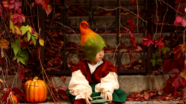 A-little-girl-in-a-gnome-costume-is-surprised-by-something-next-to-a-red-plant