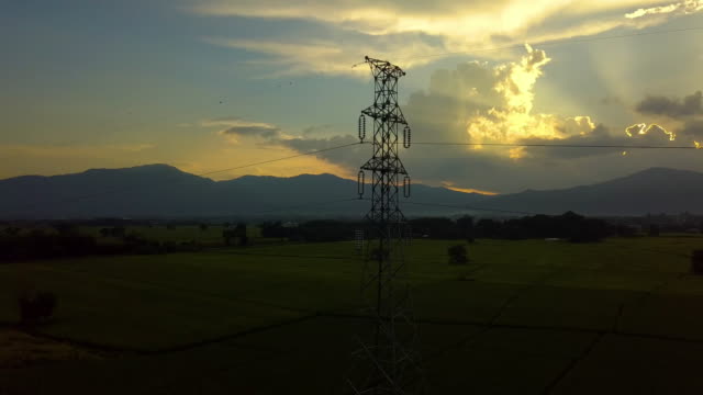 Fliegen-auf-und-rund-um-den-hohen-Spannung-Strom-Turm-mit-Sonnenuntergang
