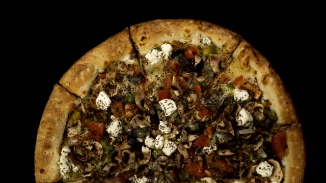 Rotierende-Pizza-mit-geräucherter-Wurst-und-Oliven-auf-einem-schwarzen-Hintergrund.-Ansicht-von-oben-Mitte-Orientierung