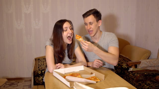 Schöne-Frau-und-Mann-zu-Hause-Pizza-essen
