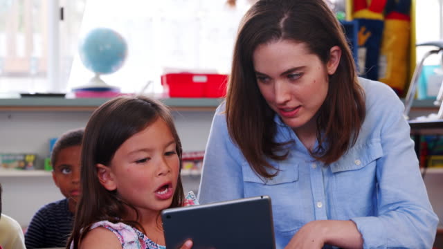 Teacher-and-girl-in-elementary-school-using-tablet-computer