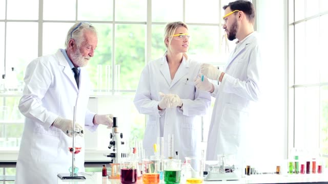 Science-teacher-and-students-team-working-with-chemicals-in-lab