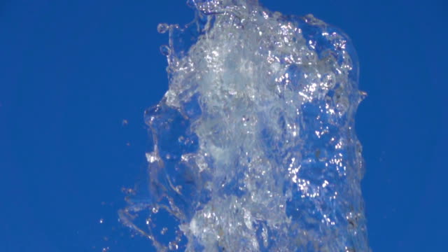 Ein-Spritzer-klare-Eiswasser.-Nahaufnahme-des-Lichts-Spritzwasser-im-sonnigen-Brunnen-im-Park-im-Sommer-auf-blauen-Himmelshintergrund.--Wasser-Strömung-der-Brunnen-Fliege-sich-in-Luft-mit-vielen-Spritzern.-Slow-Motion.
