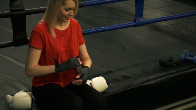 Die-Mädchen-Boxer-im-Ring-sitzt-und-glättet-die-Bandagen-an-den-Händen