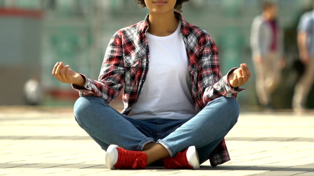 Junge-Afro-amerikanische-Frau-Meditation-Yoga-im-Lotussitz-auf-belebten-städtischen-Straße