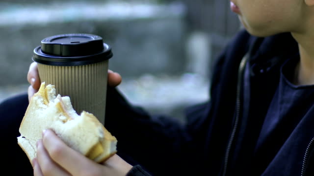 Niño-sin-hogar-comer-sandwich-y-beber-café-al-aire-libre,-la-pobreza,-closeup