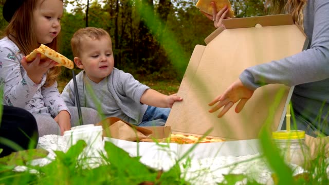 Kinder-essen-Pizza-im-Herbst-Park-auf-dem-Rasen