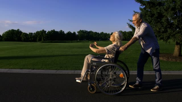 Hombre-con-esposa-en-silla-de-ruedas-disfrutando-al-aire-libre