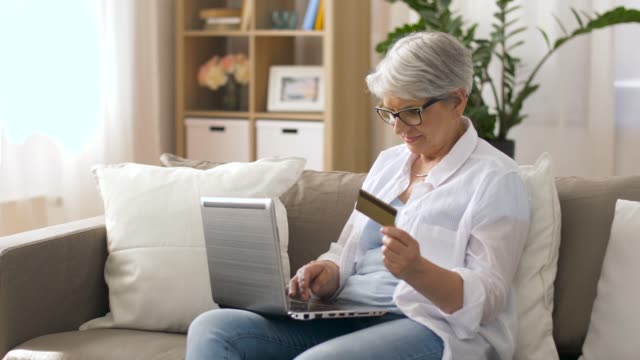 mujer-Senior-con-laptop-y-tarjeta-de-crédito-en-casa
