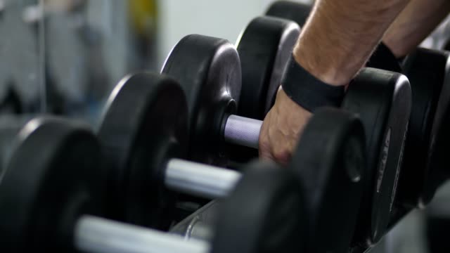 Close-up.-Hands-wraps-the-belt-on-a-dumbbell-and-take-dumbbells-4K-Slow-Mo