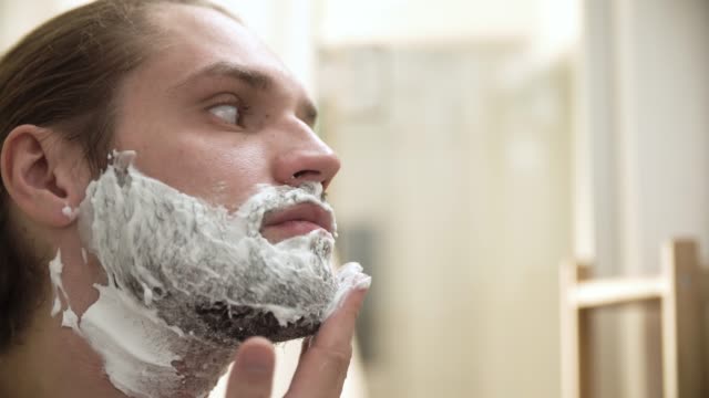 Higiene-de-los-hombres.-Aplicación-de-espuma-de-afeitar-en-Closeup-barba-hombre